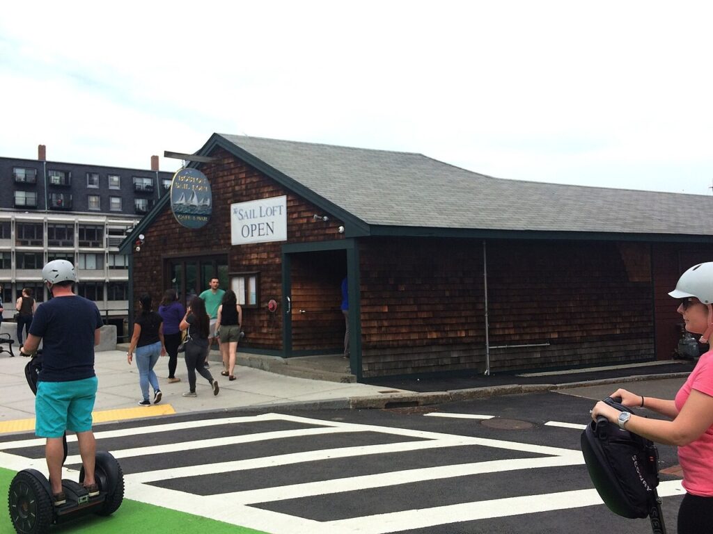 Participants in a guided Segway tour zip along down Atlantic Avenue past the Boston Sail Loft restaurant.